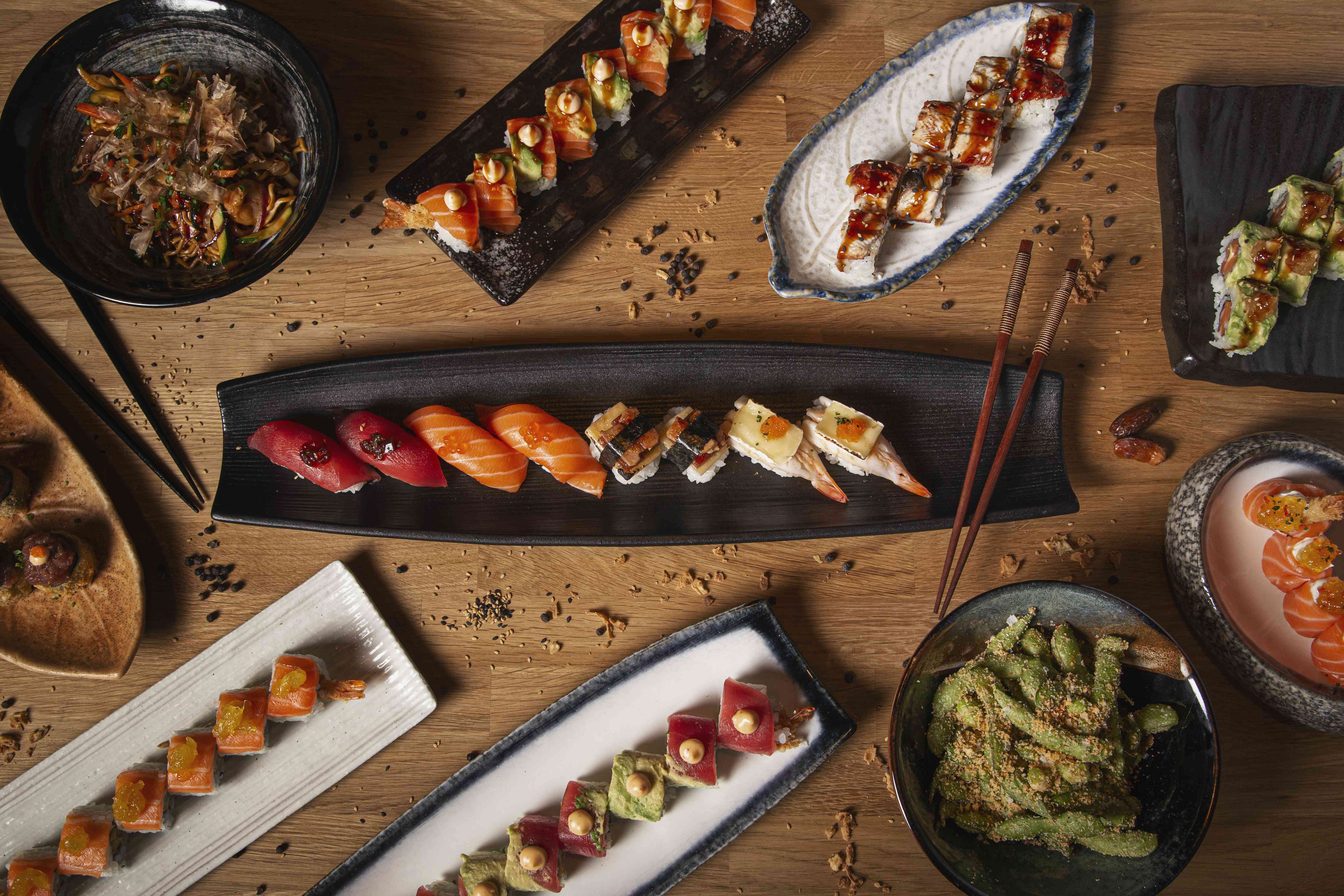 top view of a variety of sushi nigiri sashimi yakisoba and edamame on a restaurant wooden table
